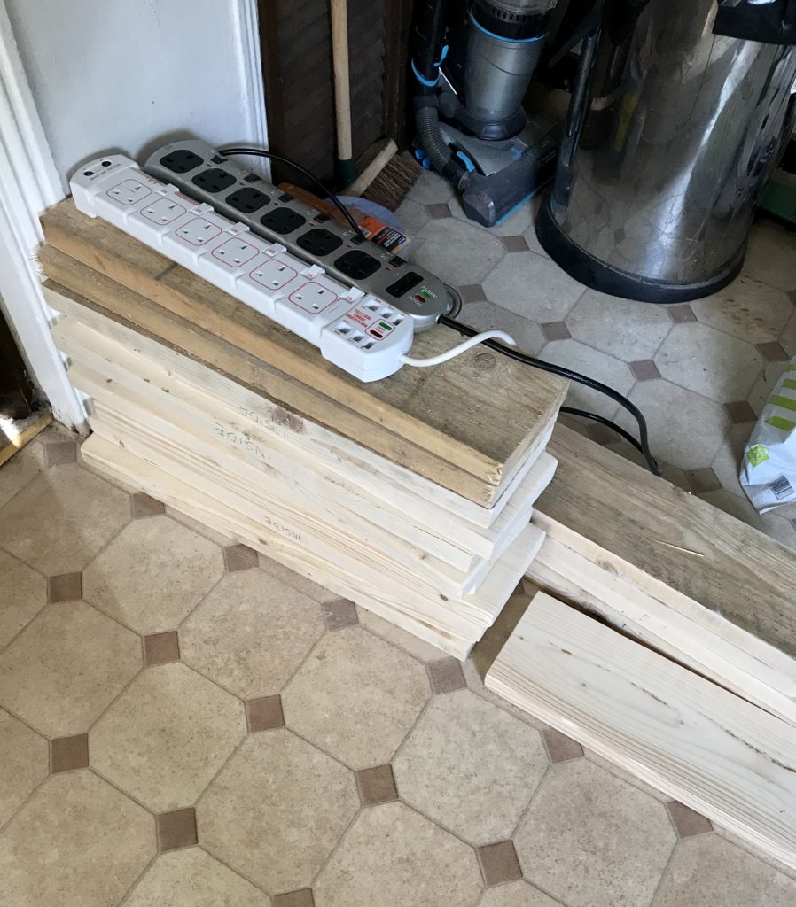 This photo shows the recycled wood, piled up in my kitchen. Some of the wood has been sanded, and some of it hasn't. The difference between the two is very stark!