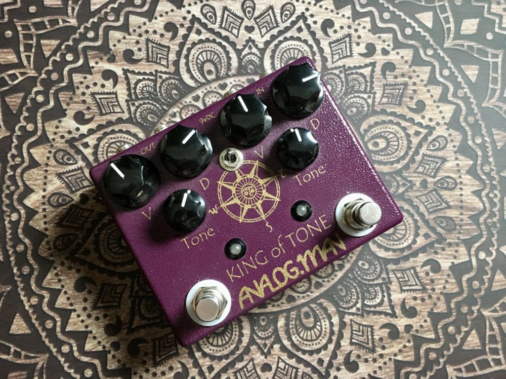 This photo shows the Analogman King of Tone pedal, looking down from above. The viewer can clearly see the top-mounted toggle switch in the middle of the pedal.