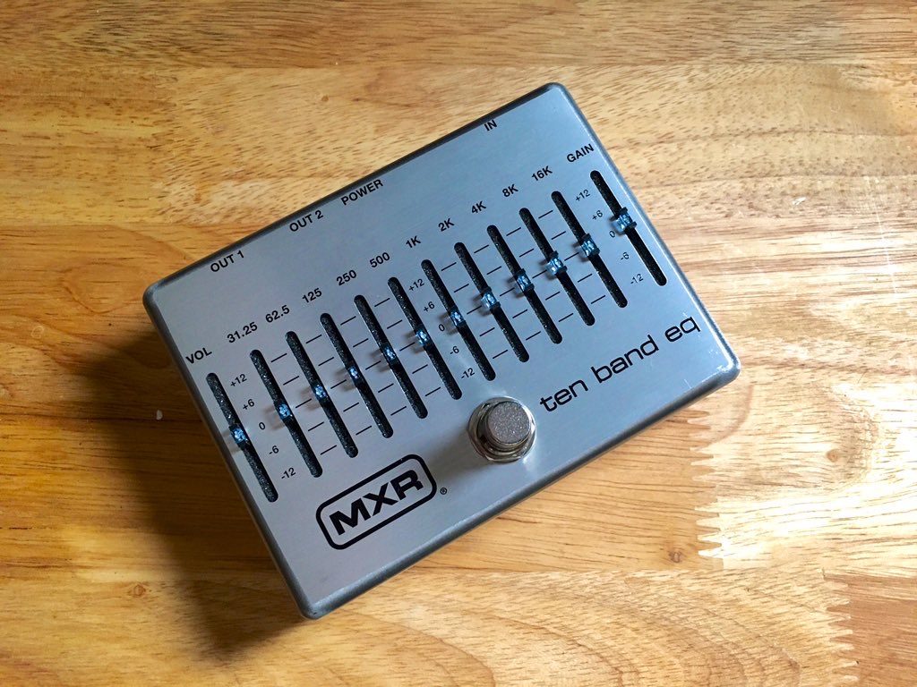 This photos is a top-down shot of the 10 band EQ pedal from MXR. All 10 EQ sliders are shown, along with a volume slider on the far-left, and a gain slider on the far-right of the pedal.