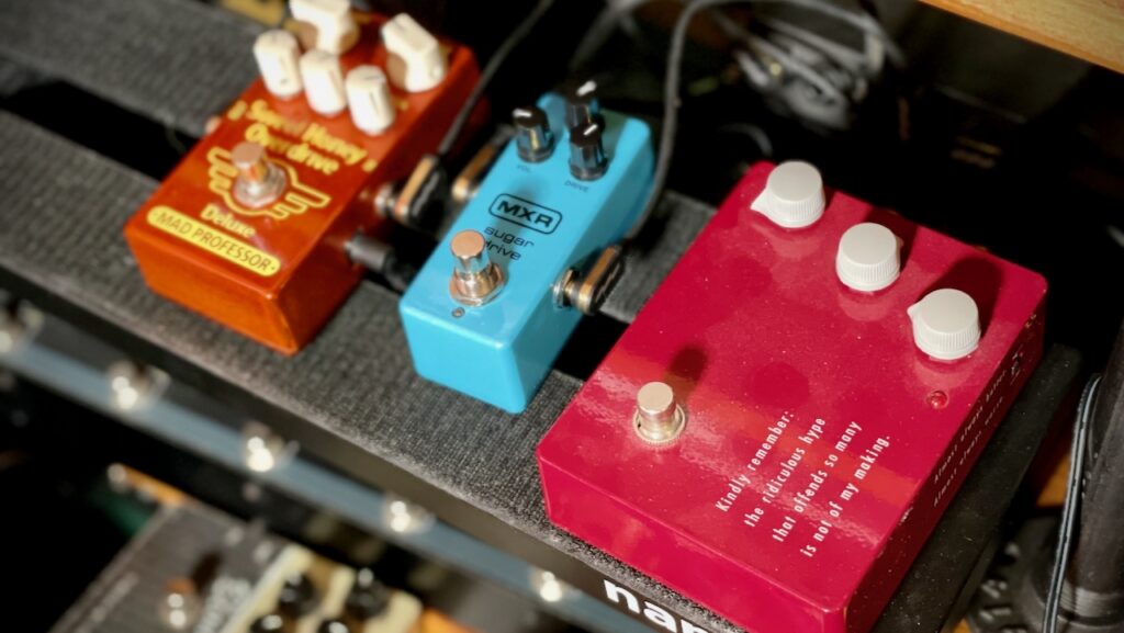 This photo shows three guitar effects pedals on my pedal board.

On the left is the Sweet Honey Overdrive pedal. In the middle is the MXR Sugar Drive (the subject of this blog post). On the right, a somewhat dusty Klon KTR.