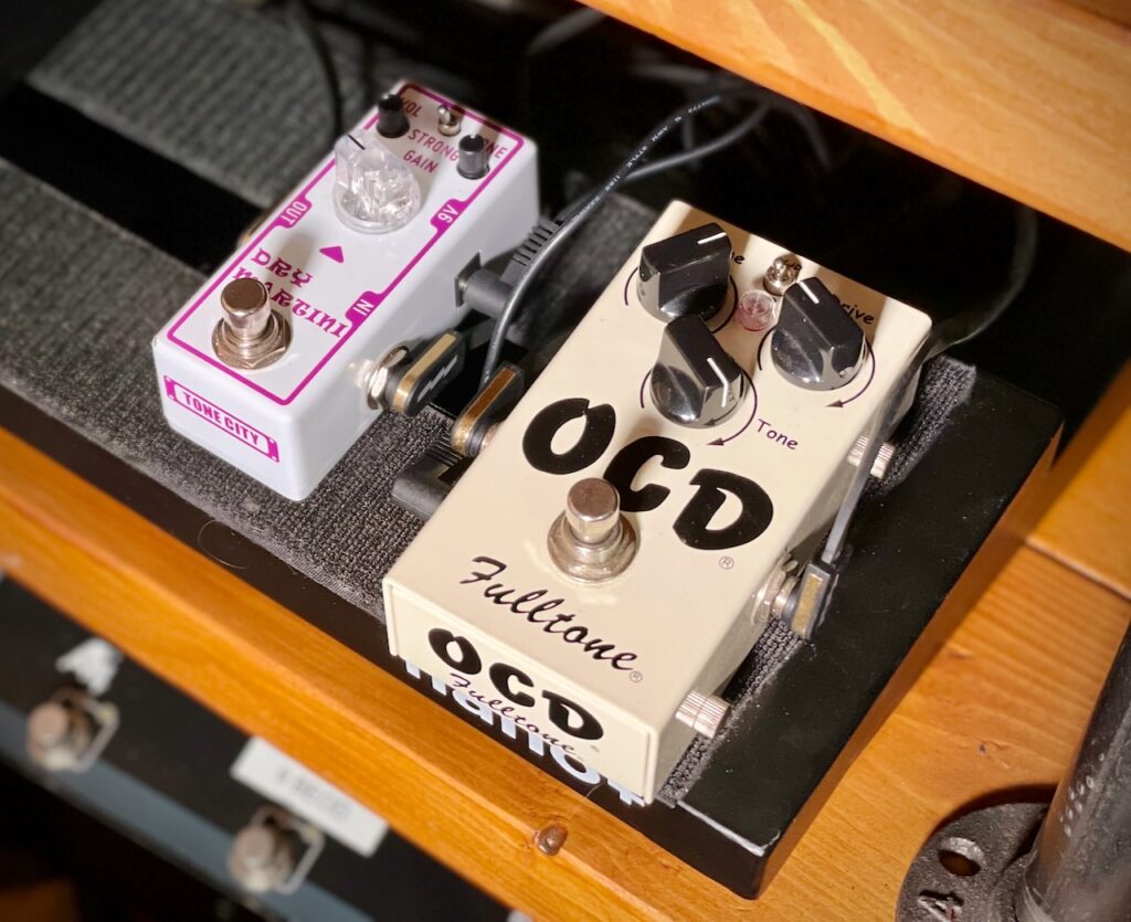 This photo shows two pedals on my pedalboard.

On the left in shades of purple and pink is Tone City's Dry Martini mini pedal.

On the right in a warm cream colour is Fulltone's OCD pedal.